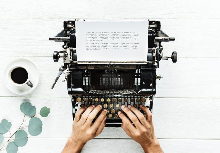 Typing at manual typewriter with coffee cup nearby