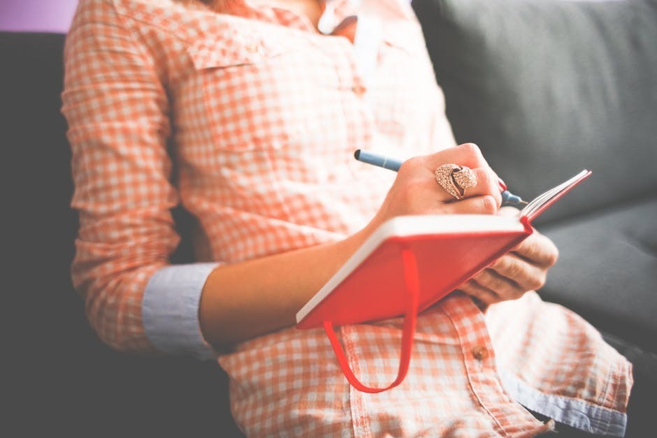 woman writing in journal with pen