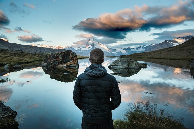 calm man looking at pond with mountain in background