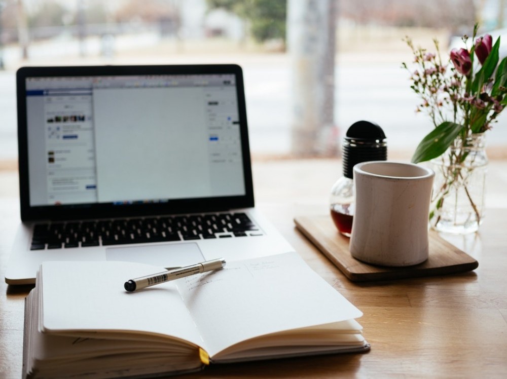 computer and journal on desk with coffee mug