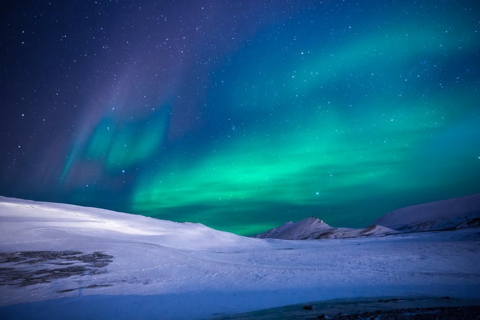 aurora borealis with green light over snowy land