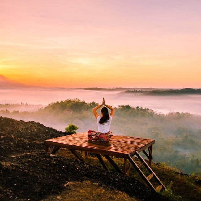 woman watching sunrise with raised arms